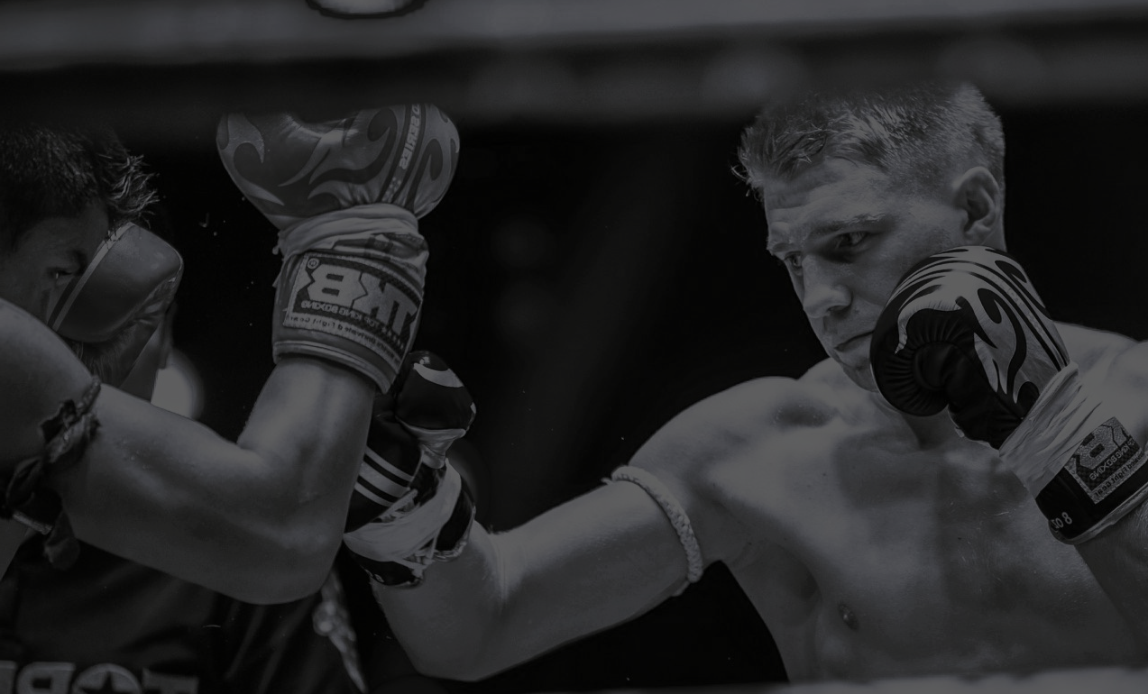 Two boxers in a boxing ring with one boxer delivering a punch.