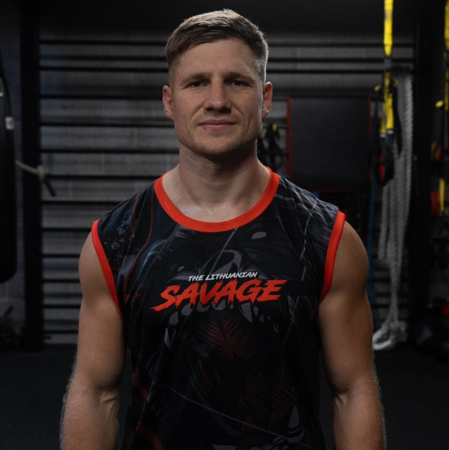 Man wearing a black tank top with 'SAVAGE' printed on it in a gym setting