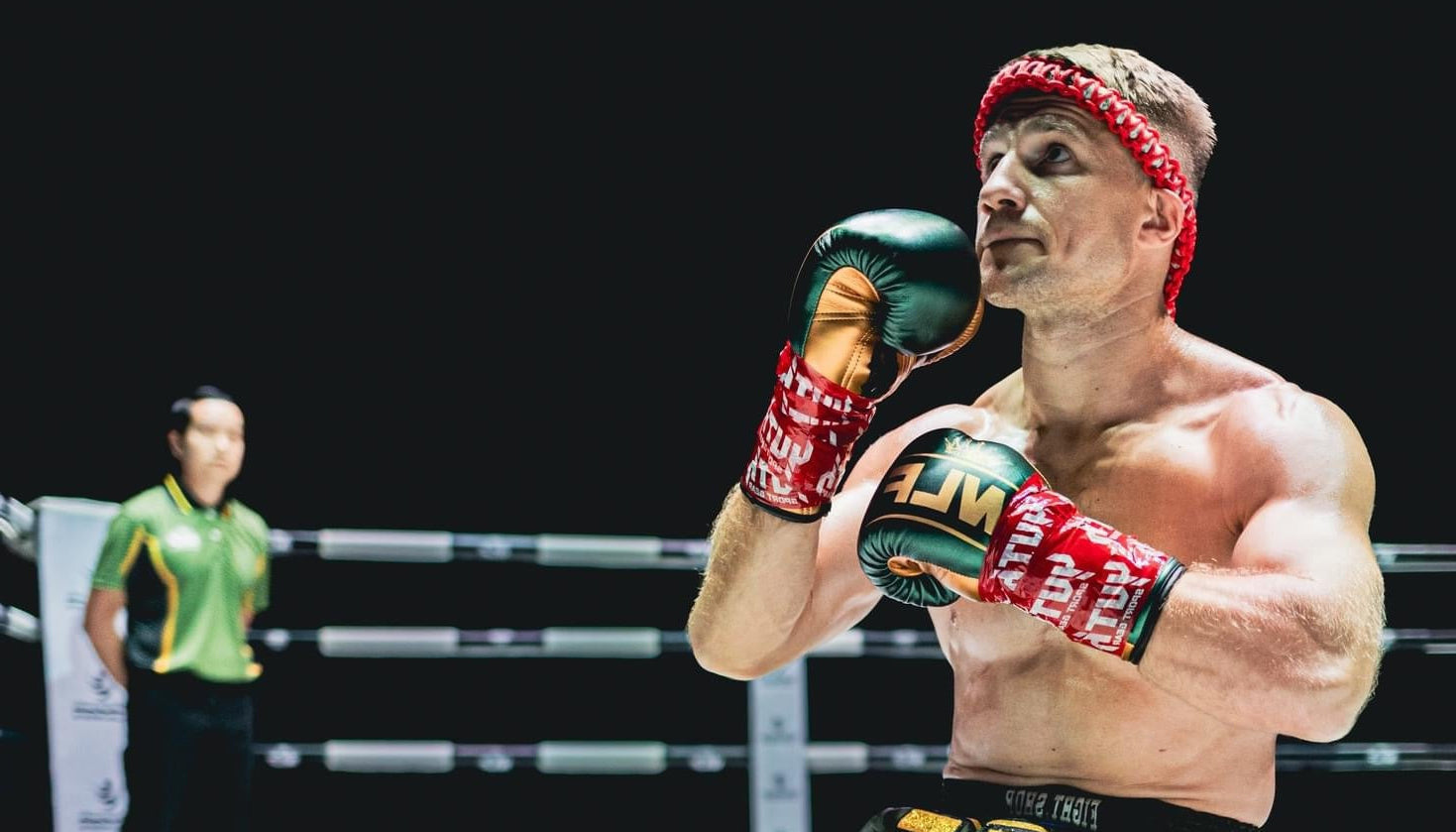 Boxer in a fighting stance with gloves on a boxing ring.